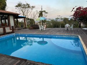a swimming pool with a table and chairs and an umbrella at Recanto Cravo e Canela in Itatiaia