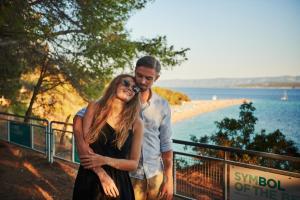 a man and a woman standing next to a beach at Bluesun Hotel Borak in Bol
