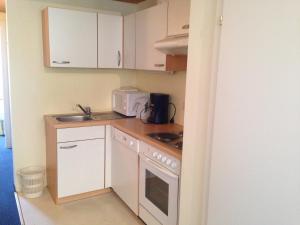 eine kleine Küche mit weißen Schränken und einem Waschbecken in der Unterkunft Appartements im Forsthaus in Strobl