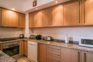 a kitchen with wooden cabinets and a microwave at Top-floor 2 BR holiday home with sea view and pool in Luz +13 photos