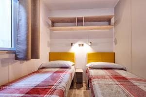 2 camas en una habitación con paredes blancas en Campeggio Amici di Lazise, en Lazise