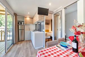 拉齊塞的住宿－Campeggio Amici di Lazise，厨房以及带红色和白色桌布的桌子的用餐室。