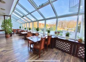 a restaurant with tables and chairs and large windows at Mansfelder Hof in Lutherstadt Eisleben