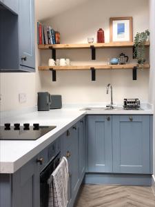 a kitchen with blue cabinets and a sink at Newly renovated seaside townhouse with logburner in Nairn