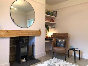 a mirror over a fireplace in a living room with a chair at Newly renovated seaside townhouse with logburner in Nairn