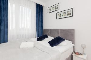 a bedroom with two white beds with blue curtains at Warsaw Kotsisa Apartments with Parking by Renters in Warsaw