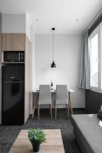 een keuken met een zwarte koelkast en een tafel met stoelen bij WallStreet, The Luxury Suites in Thessaloniki