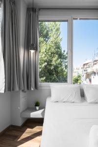 a bedroom with a white bed and a window at WallStreet, The Luxury Suites in Thessaloniki