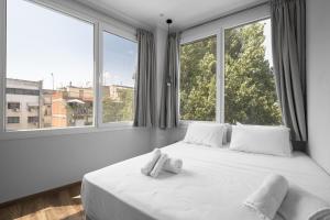 a bedroom with a white bed with two windows at WallStreet, The Luxury Suites in Thessaloniki