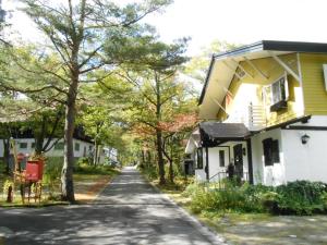 ulica w mieście z żółtym domem w obiekcie Pension Nugget Inn w mieście Hakuba