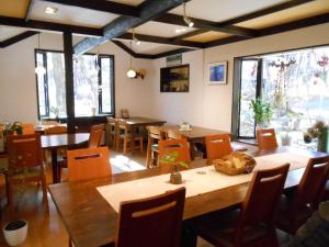 un comedor con mesas, sillas y ventanas en Pension Nugget Inn, en Hakuba