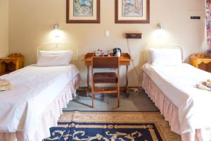 a room with two beds and a desk with a chair at Dullstroom Inn in Dullstroom