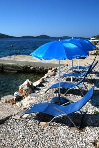 due sedie blu e un ombrellone su una spiaggia di Family friendly apartments with a swimming pool Kaprije - 17692 a Kaprije (Caprie)