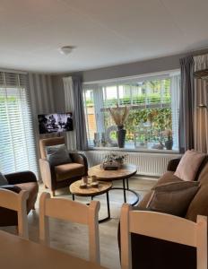 een woonkamer met een bank, stoelen en een tafel bij Luxe Chalet met prachtig terras op de Veluwe , veel privacy in Hoenderloo
