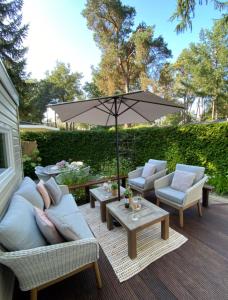 un patio con sofás y una mesa con sombrilla en Luxe Chalet met prachtig terras op de Veluwe , veel privacy, en Hoenderloo