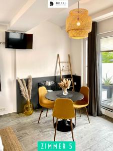 ein Esszimmer mit einem schwarzen Tisch und gelben Stühlen in der Unterkunft Dock 6 - Cuxhaven in Cuxhaven