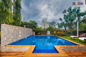 a swimming pool with blue water in a yard at EKOSTAY - Cozy Nest Villa in Karjat