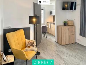 ein Wohnzimmer mit einem gelben Stuhl und eine Küche in der Unterkunft Dock 6 - Cuxhaven in Cuxhaven