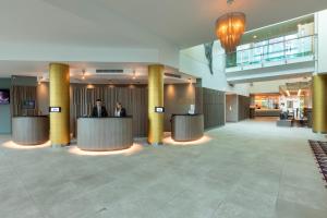 a lobby with two people standing at a counter at Crowne Plaza Birmingham NEC by IHG in Bickenhill