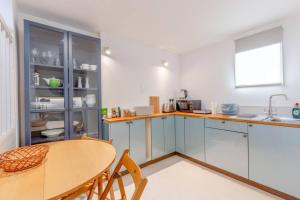 cocina con armarios azules, mesa y ventana en Cosy 1 Bedroom Apartment near Wimbledon station, en Londres