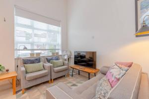uma sala de estar com um sofá e duas cadeiras em Cosy 1 Bedroom Apartment near Wimbledon station em Londres