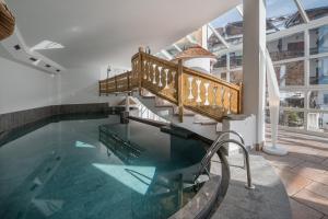 an indoor swimming pool with a stairway and a swimming pool at Hotel Mühlenerhof in Campo Tures