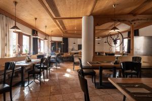 a restaurant with wooden ceilings and tables and chairs at Hotel Mühlenerhof in Campo Tures
