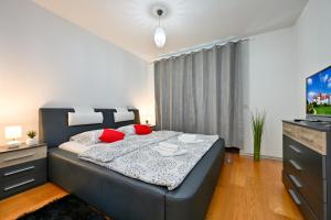 a bedroom with a large bed with red pillows and a television at Exclusive apartment in Varaždin in Varaždin