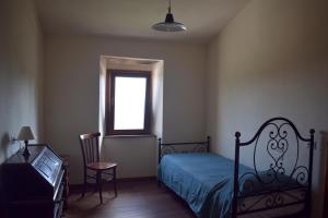 een slaapkamer met een bed, een raam en een stoel bij Agriturismo Menghino in Nievole