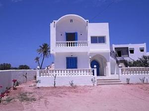 a white house with a fence and a palm tree at 2 bedrooms apartement with enclosed garden and wifi at Djerba Midoun 1 km away from the beach in Aghīr