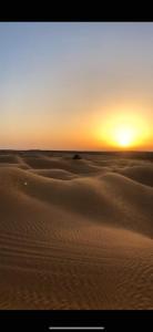 a sunset over the sand dunes in the desert at 2 bedrooms apartement with enclosed garden and wifi at Djerba Midoun 1 km away from the beach in Aghīr