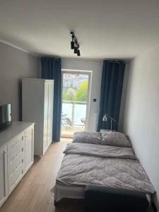 1 dormitorio con 1 cama con cortinas azules y ventana en Apartament na Okrzei, en Sandomierz