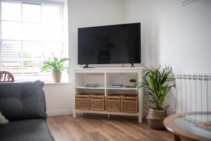a living room with a television on a white cabinet at End House Inverness in Inverness