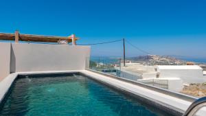 a swimming pool on the side of a house with the ocean at Lami Traditional Windmill - With Private pool and Jacuzzi in Pirgos