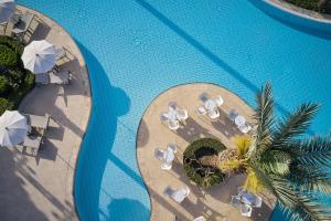 einen Blick über einen Pool mit Stühlen und Sonnenschirmen in der Unterkunft ROBINSON Cyprus in Alaminos