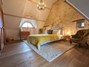 um quarto com uma cama e uma parede de pedra em Maison typique bretonne avec toit de chaume em Camors
