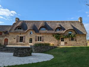 uma grande casa de pedra com telhado em Maison typique bretonne avec toit de chaume em Camors
