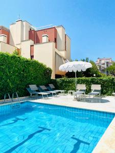 a swimming pool with chairs and an umbrella at Noha Suite Hotel in Riccione