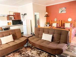 sala de estar con 2 sofás marrones y cocina en Havana Nights en Graskop