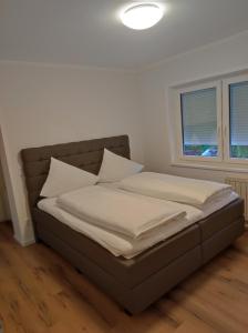 - un lit avec des draps et des oreillers blancs dans l'établissement Sommerresidenz 9210, à Pörtschach am Wörthersee