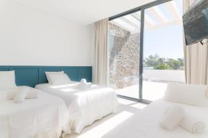 Duas camas brancas num quarto com uma janela grande em Villa Melissa em Tróia mais 40 fotografias
