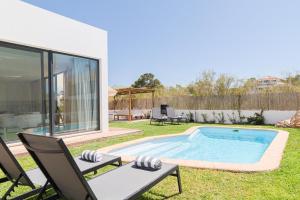 uma piscina num quintal com duas cadeiras e uma mesa em Villa Melissa em Tróia