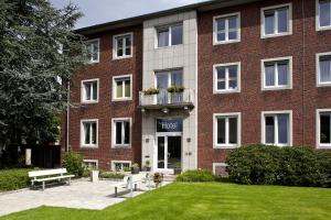 a large brick building with a lawn in front of it at Hotel Haus vom Guten Hirten in Münster