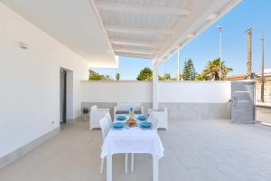 uma sala de jantar branca com uma mesa e cadeiras em Residence Marelena by BarbarHouse em Casalabate