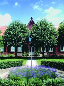 une maison dotée d'un jardin avec des fleurs violettes en face de celle-ci dans l'établissement Seehotel Am Neuklostersee, à Neukloster
