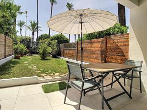 stół i krzesła z parasolem na patio w obiekcie Beautiful 1 bedroom with garden on the Croisette 254 w Cannes