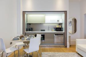 eine Küche und ein Esszimmer mit einem Tisch und weißen Stühlen in der Unterkunft The Dorset Suite - Stylish New 1 Bedroom Apartment In Marylebone in London