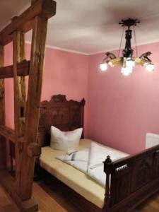 a bedroom with a wooden bed and pink walls at Rittergut Schloss Niederforchheim in Forchheim