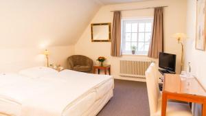 a bedroom with a bed and a desk and a television at Meyers Hotel Hittfeld in Seevetal