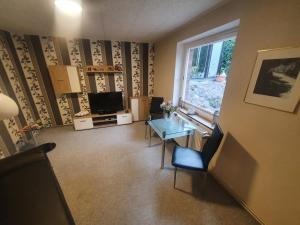 a living room with a table and a television at Ferienwohnung zur Kühlung in Wittenbeck